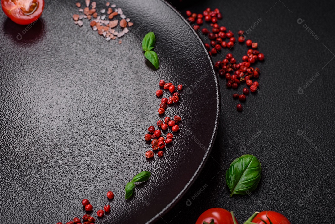 Ingredientes para cozinhar tomate cereja, sal, especiarias e ervas sobre um fundo escuro de concreto