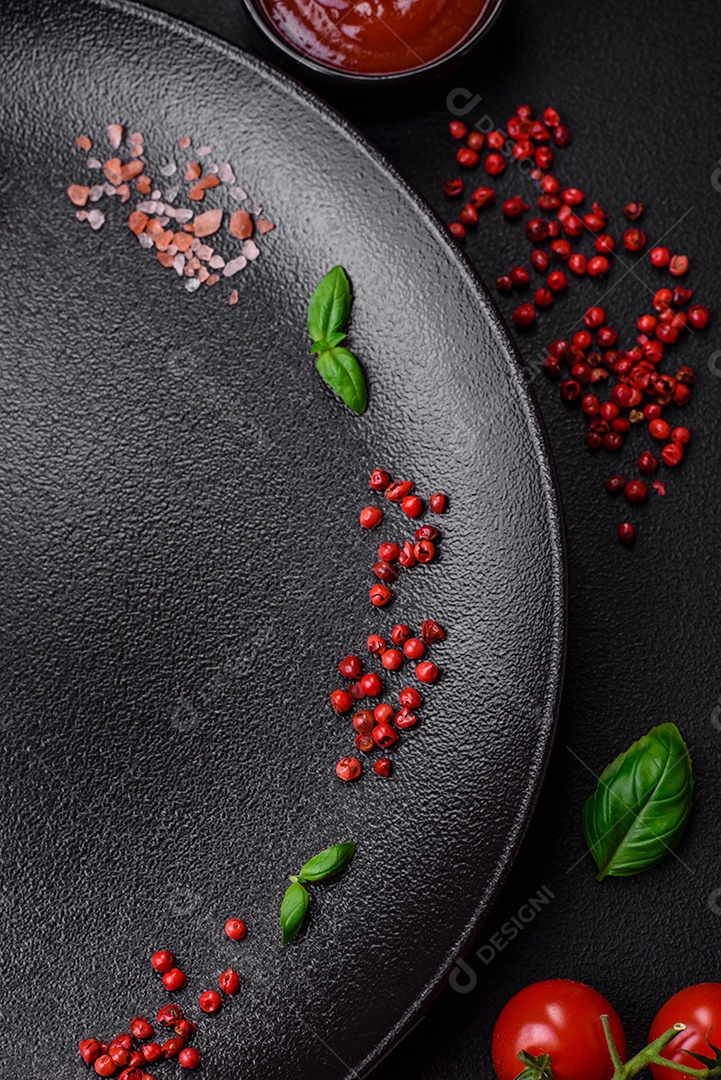 Ingredientes para cozinhar tomate cereja, sal, especiarias e ervas sobre um fundo escuro de concreto