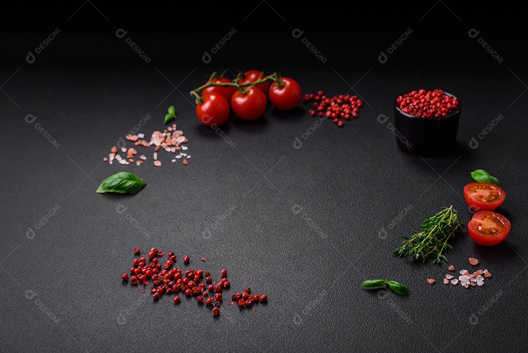 Ingredientes para cozinhar tomate cereja, sal, especiarias e ervas sobre um fundo escuro de concreto