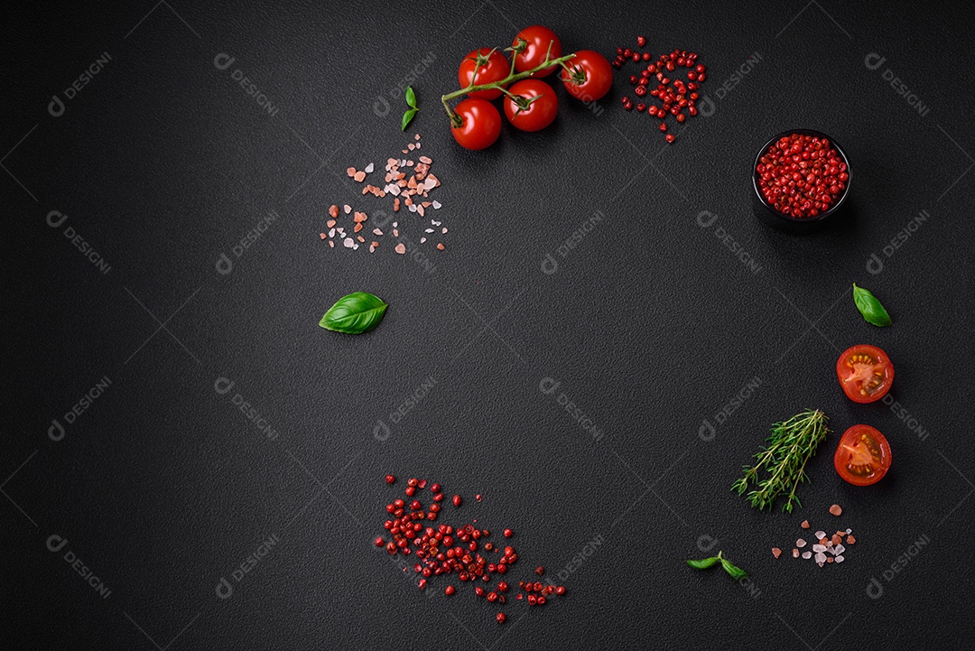 Ingredientes para cozinhar tomate cereja, sal, especiarias e ervas sobre um fundo escuro de concreto