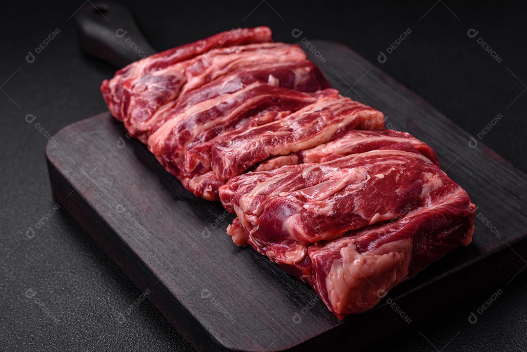 Costelas de carne crua fresca com sal, especiarias e ervas preparadas para grelhar