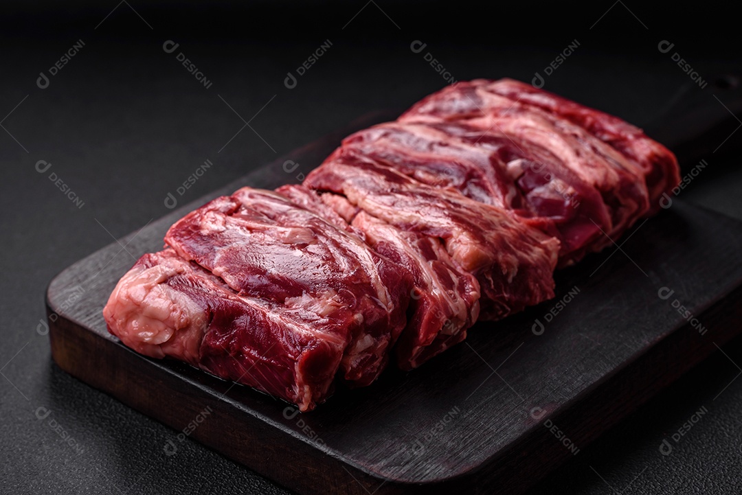 Costelas de carne crua fresca com sal, especiarias e ervas preparadas para grelhar