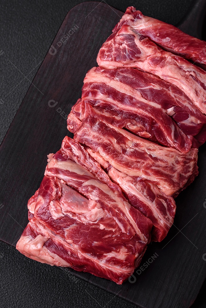 Costelas de carne crua fresca com sal, especiarias e ervas preparadas para grelhar