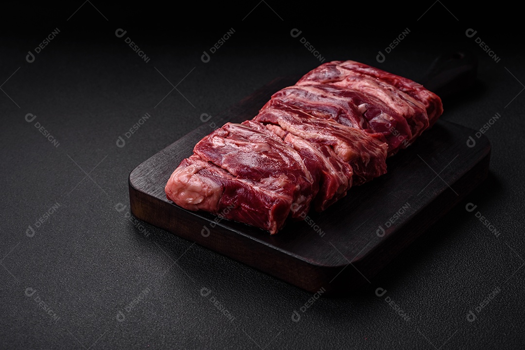 Costelas de carne crua fresca com sal, especiarias e ervas preparadas para grelhar