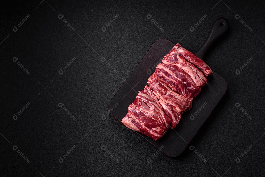 Costelas de carne crua fresca com sal, especiarias e ervas preparadas para grelhar