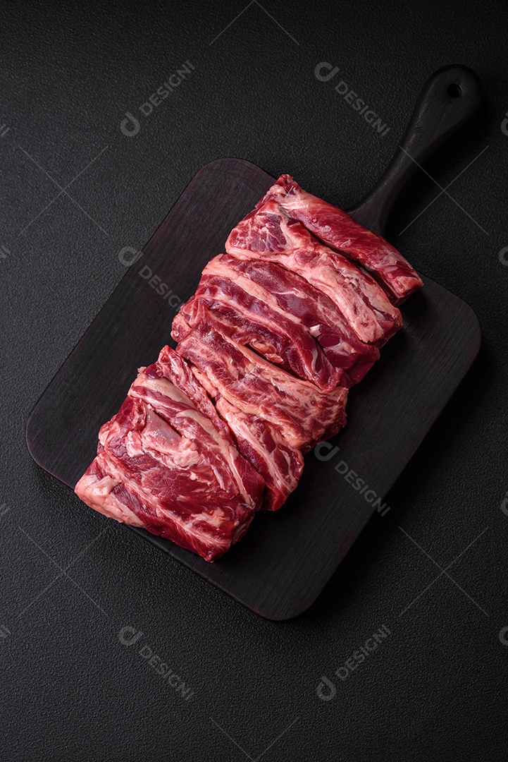 Costelas de carne crua fresca com sal, especiarias e ervas preparadas para grelhar