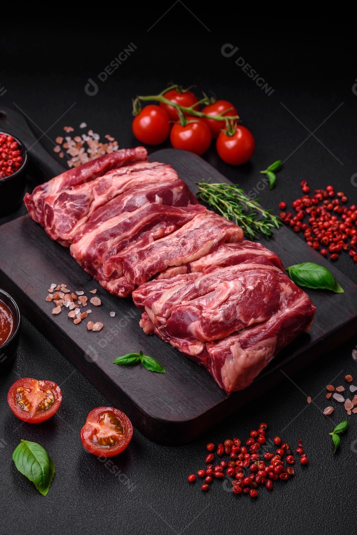 Costelas de carne crua fresca com sal, especiarias e ervas preparadas para grelhar