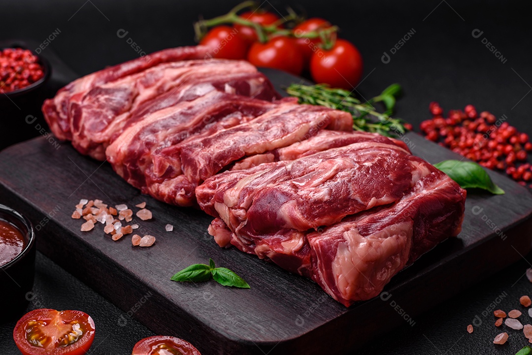 Costelas de carne crua fresca com sal, especiarias e ervas preparadas para grelhar