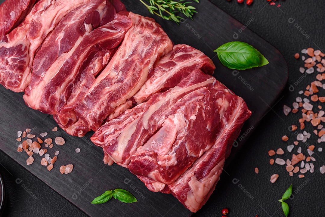 Costelas de carne crua fresca com sal, especiarias e ervas preparadas para grelhar