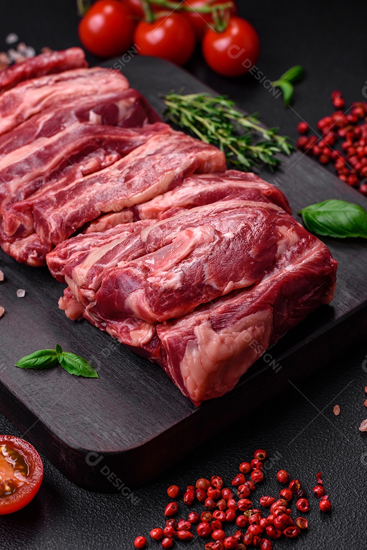 Costelas de carne crua fresca com sal, especiarias e ervas preparadas para grelhar
