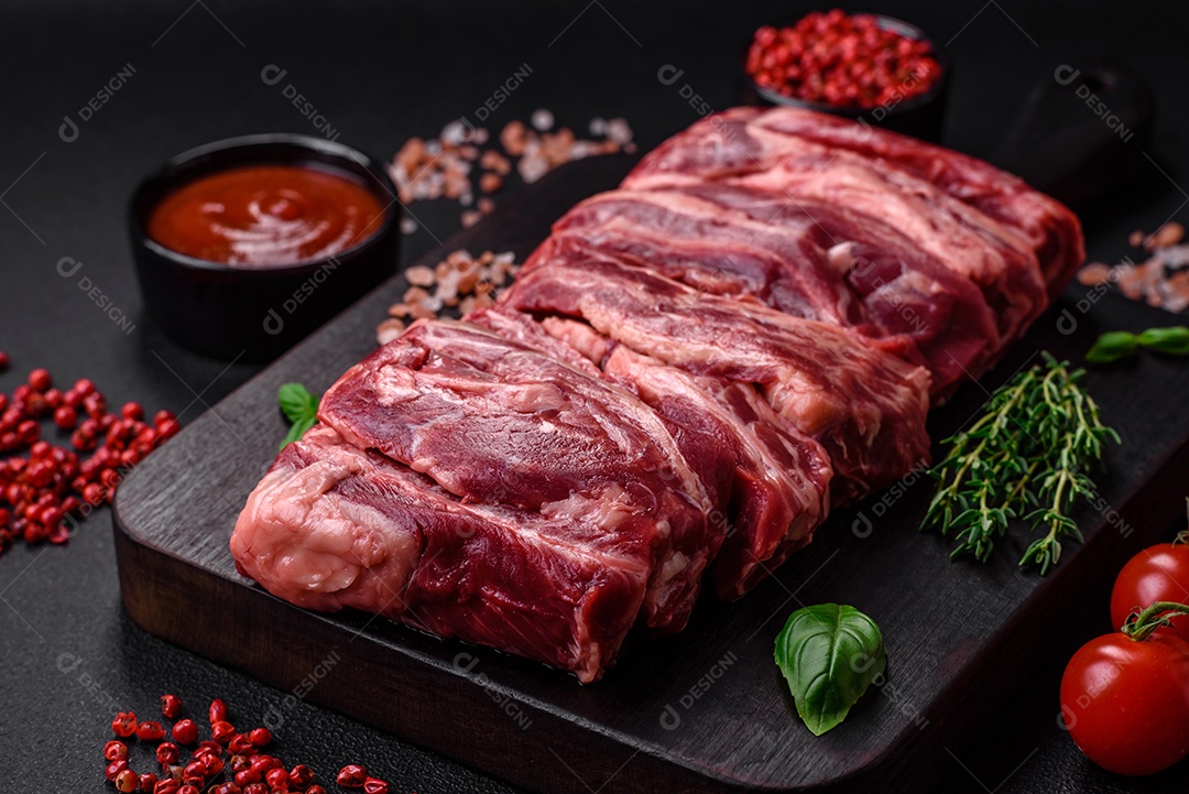 Costelas de carne crua fresca com sal, especiarias e ervas preparadas para grelhar