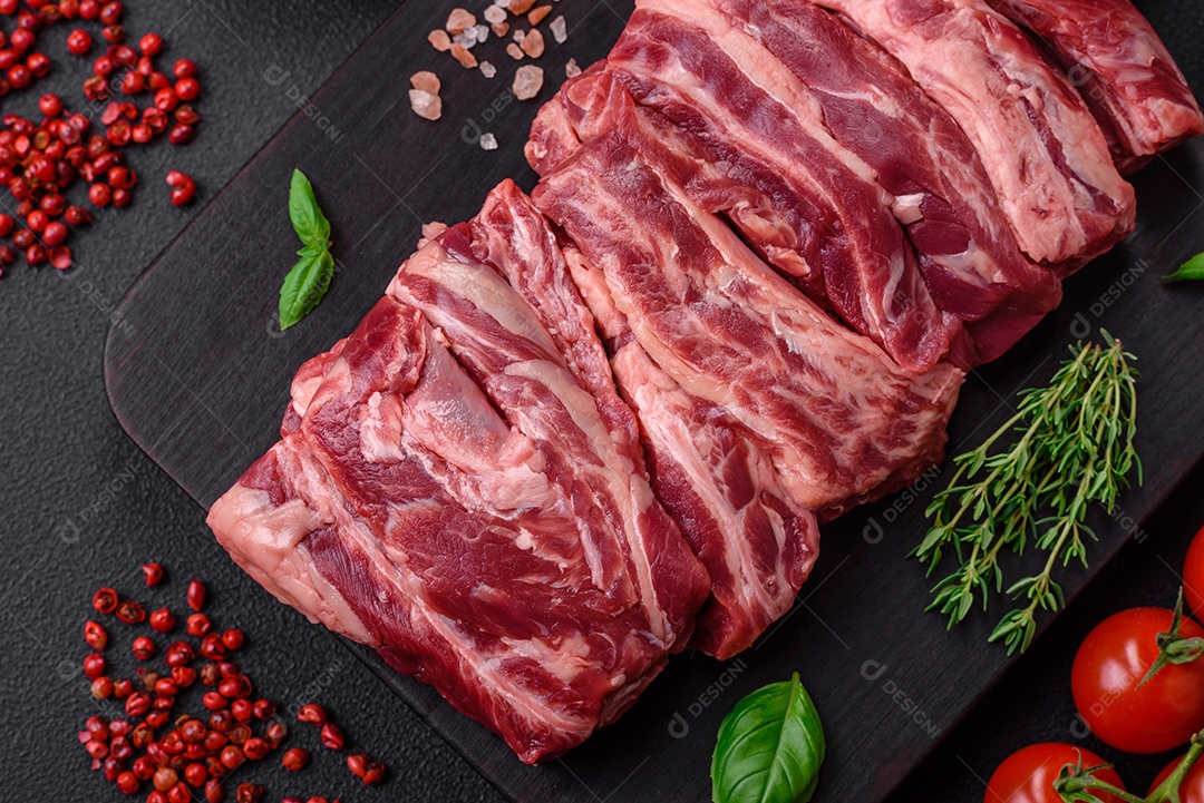 Costelas de carne crua fresca com sal, especiarias e ervas preparadas para grelhar