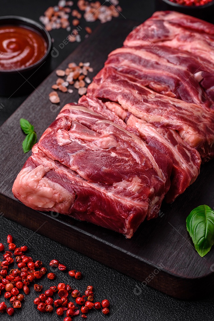 Costelas de carne crua fresca com sal, especiarias e ervas preparadas para grelhar