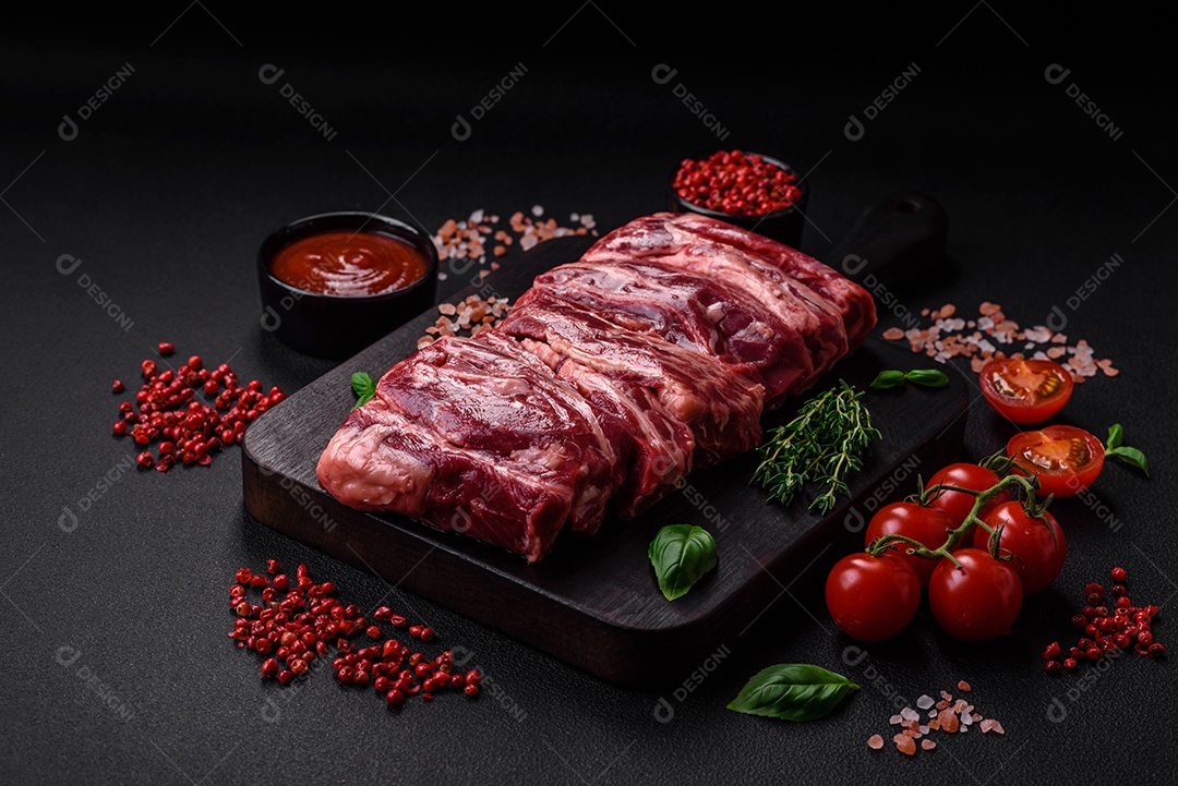 Costelas de carne crua fresca com sal, especiarias e ervas preparadas para grelhar