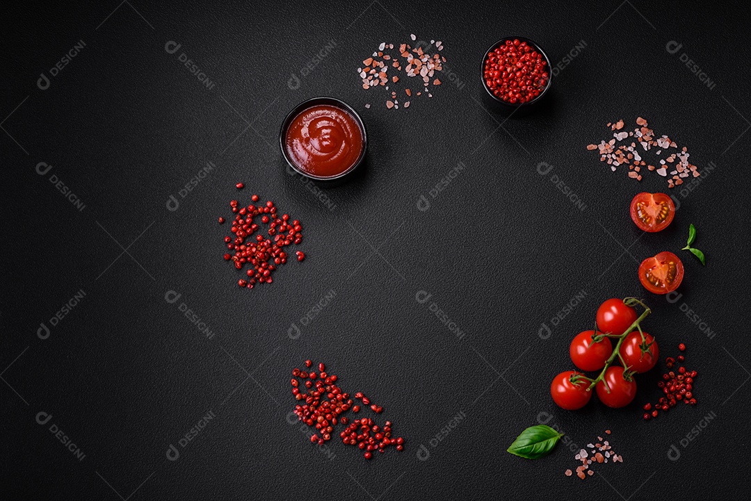 Ingredientes para cozinhar tomate cereja, sal, especiarias e ervas sobre um fundo escuro de concreto