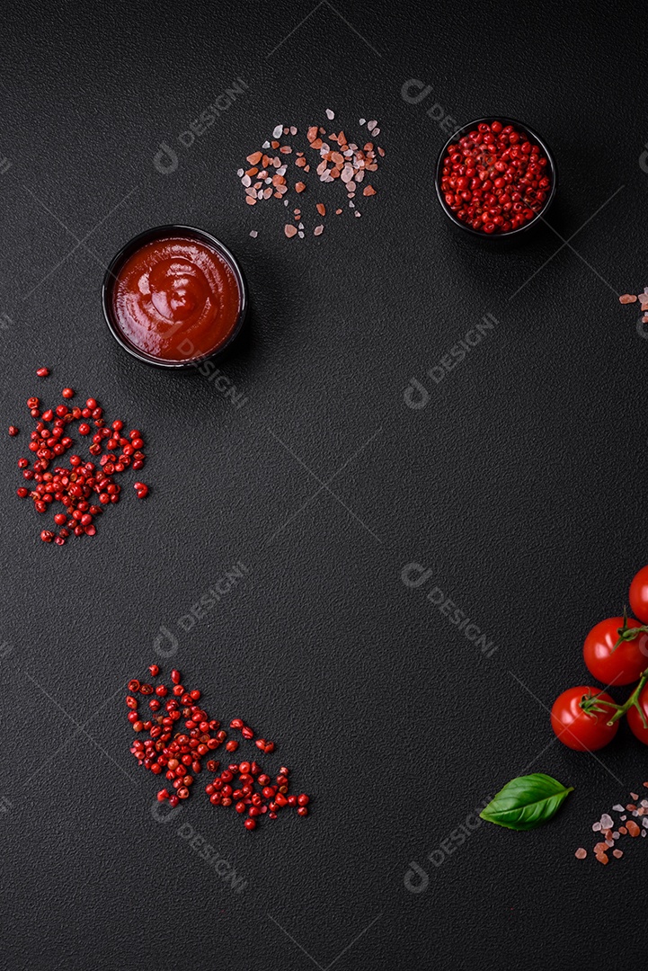 Ingredientes para cozinhar tomate cereja, sal, especiarias e ervas sobre um fundo escuro de concreto