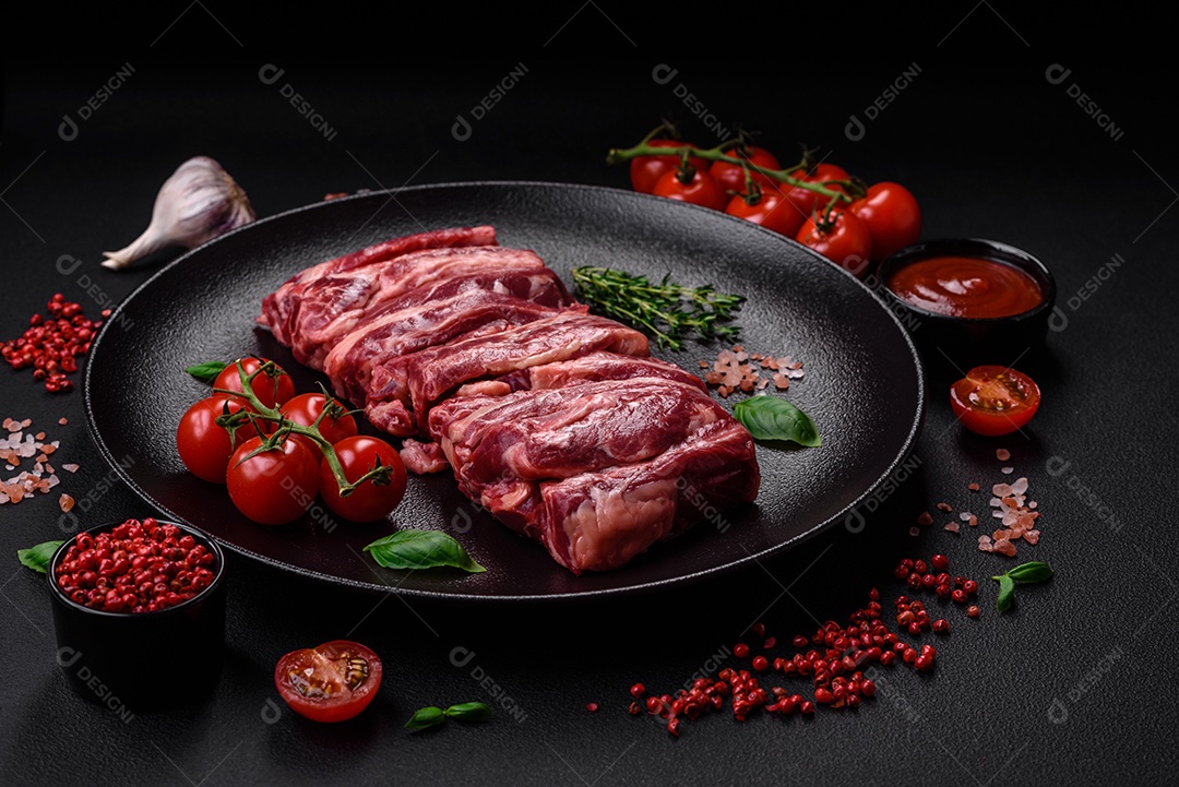 Costelas de carne crua fresca com sal, especiarias e ervas preparadas para grelhar