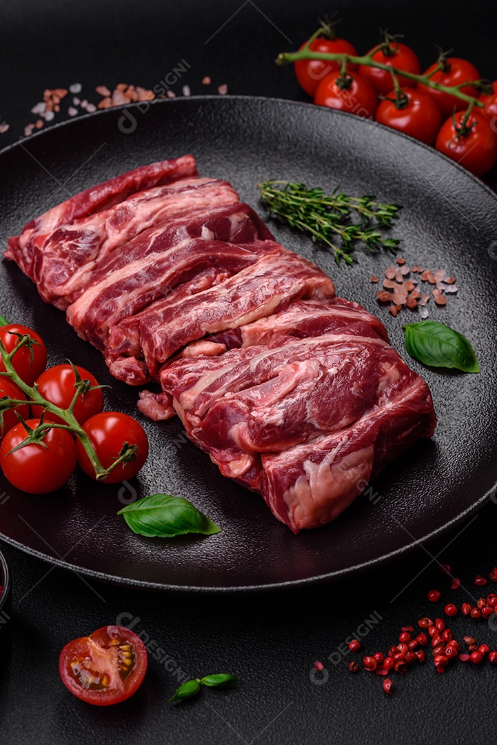 Costelas de carne crua fresca com sal, especiarias e ervas preparadas para grelhar