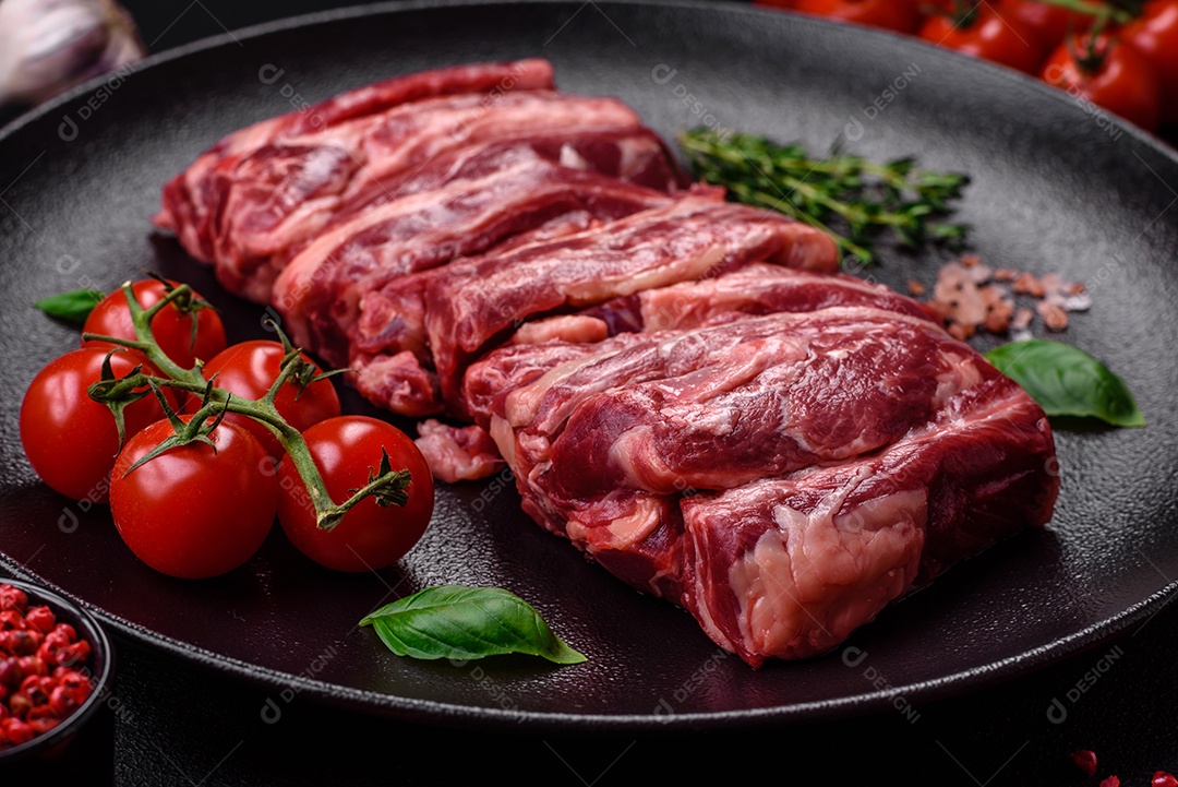 Costelas de carne crua fresca com sal, especiarias e ervas preparadas para grelhar