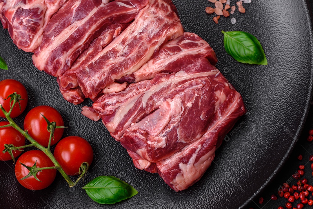 Costelas de carne crua fresca com sal, especiarias e ervas preparadas para grelhar