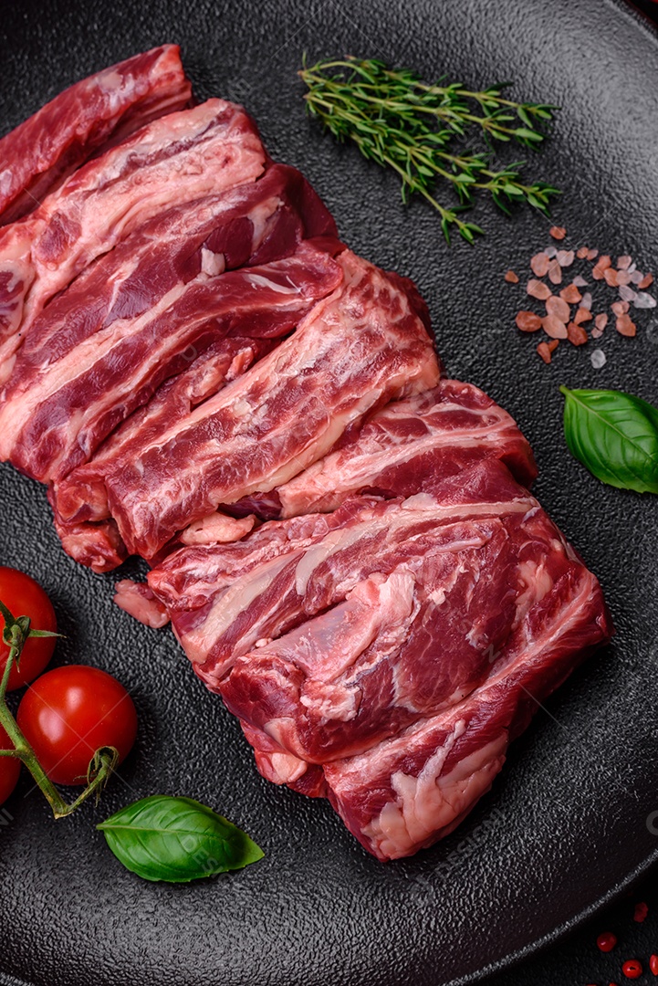 Costelas de carne crua fresca com sal, especiarias e ervas preparadas para grelhar