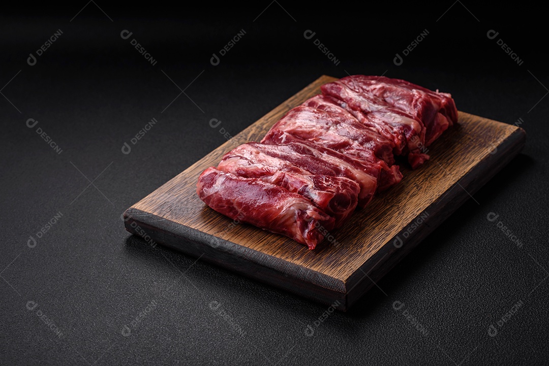 Costelas de carne crua fresca com sal, especiarias e ervas preparadas para grelhar