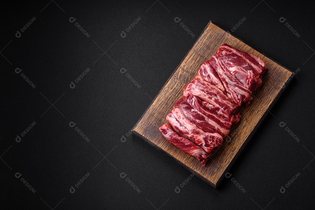 Costelas de carne crua fresca com sal, especiarias e ervas preparadas para grelhar