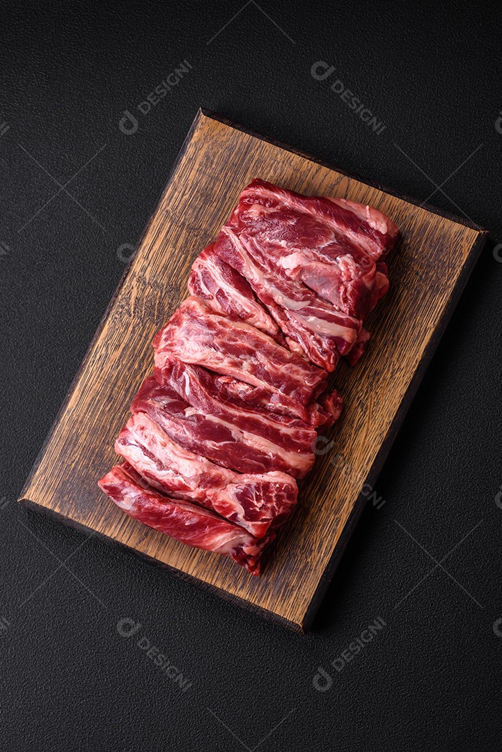 Costelas de carne crua fresca com sal, especiarias e ervas preparadas para grelhar