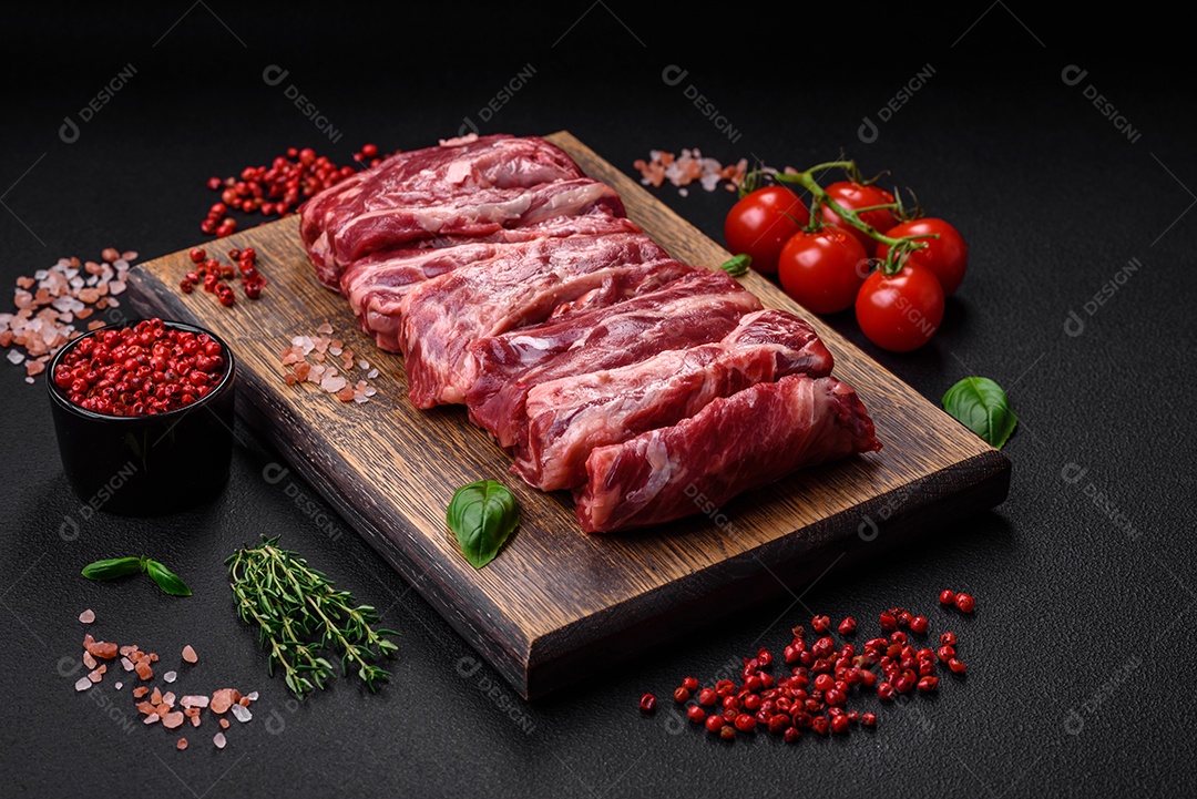 Costelas de carne crua fresca com sal, especiarias e ervas preparadas para grelhar