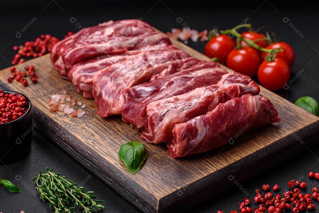 Costelas de carne crua fresca com sal, especiarias e ervas preparadas para grelhar