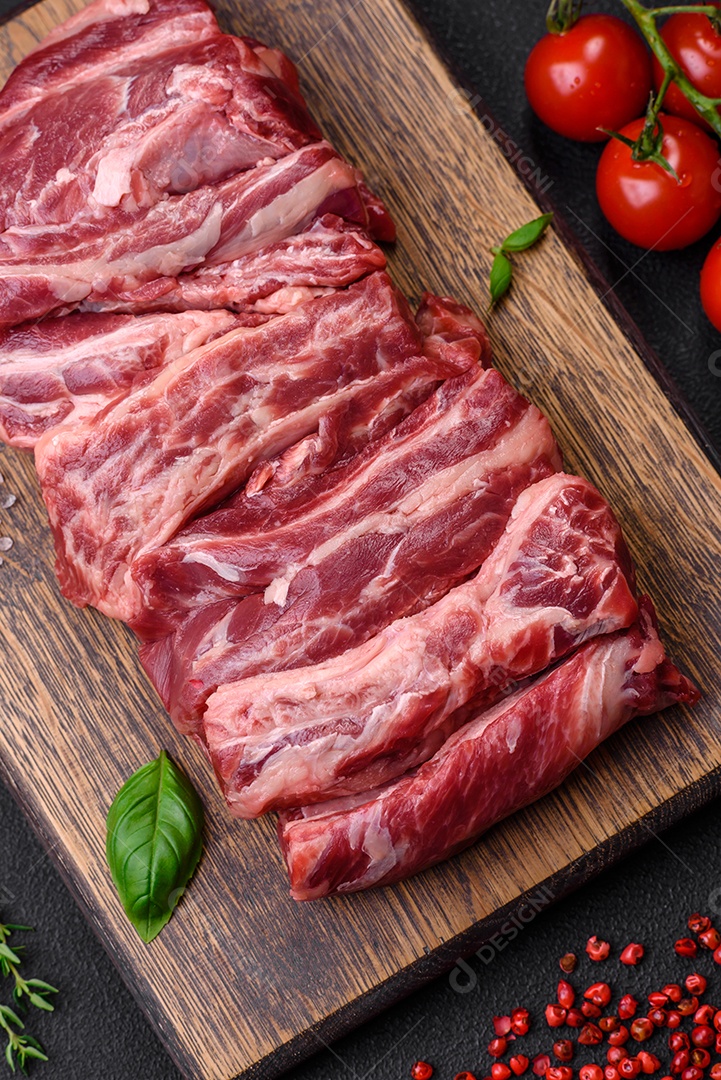 Costelas de carne crua fresca com sal, especiarias e ervas preparadas para grelhar