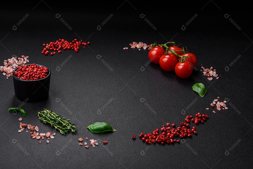 Ingredientes para cozinhar tomate cereja, sal, especiarias e ervas sobre um fundo escuro de concreto