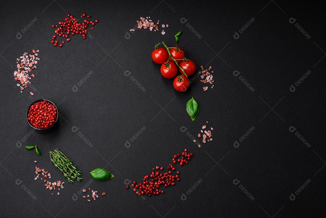 Ingredientes para cozinhar tomate cereja, sal, especiarias e ervas sobre um fundo escuro de concreto