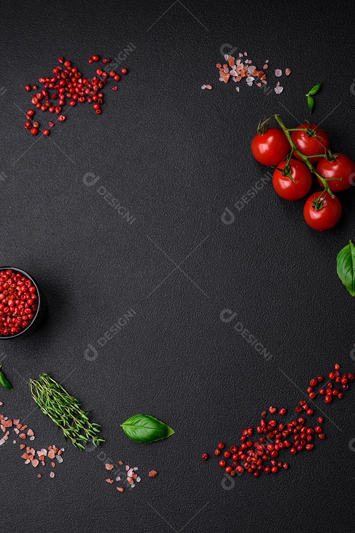 Ingredientes para cozinhar tomate cereja, sal, especiarias e ervas sobre um fundo escuro de concreto