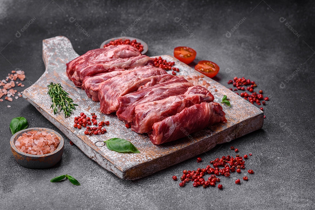 Costelas de carne crua fresca com sal, especiarias e ervas preparadas para grelhar