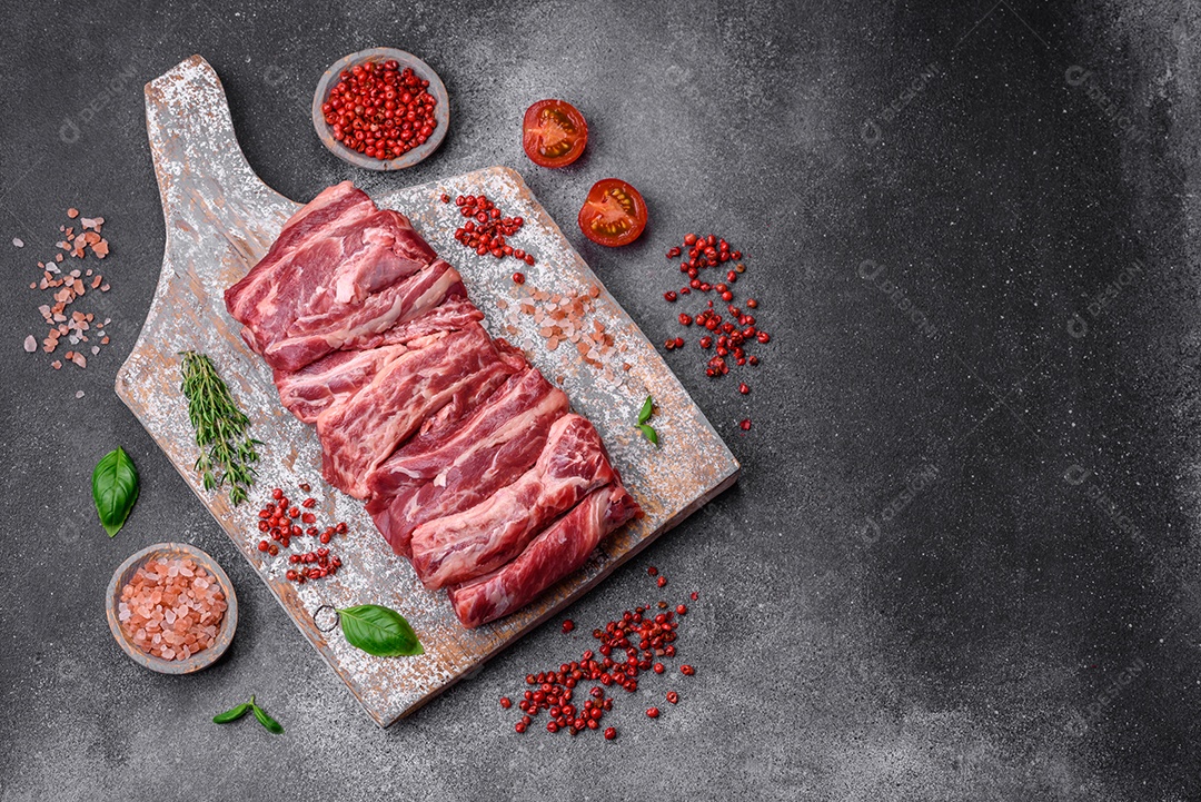 Costelas de carne crua fresca com sal, especiarias e ervas preparadas para grelhar