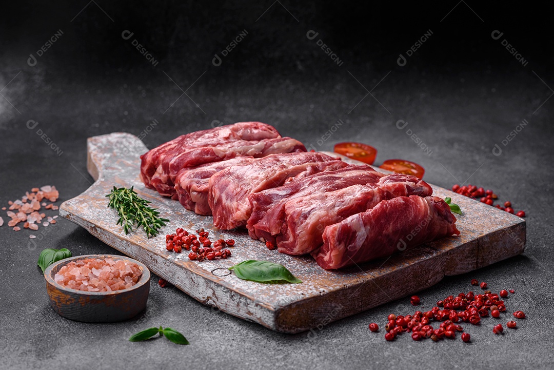 Costelas de carne crua fresca com sal, especiarias e ervas preparadas para grelhar