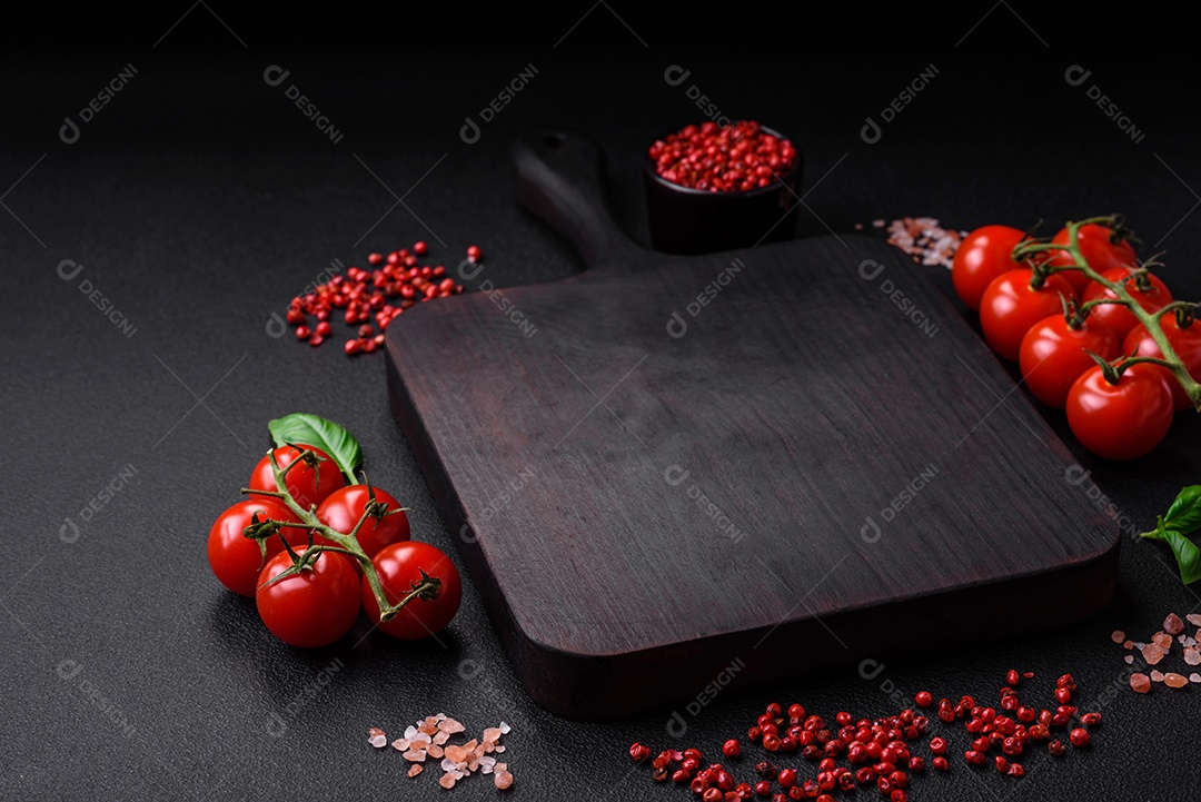 Ingredientes para cozinhar tomate cereja, sal, especiarias e ervas sobre um fundo escuro de concreto