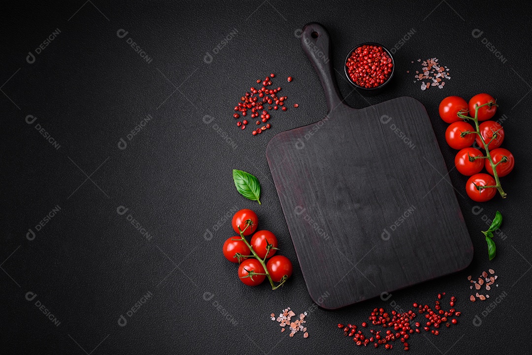 Ingredientes para cozinhar tomate cereja, sal, especiarias e ervas sobre um fundo escuro de concreto