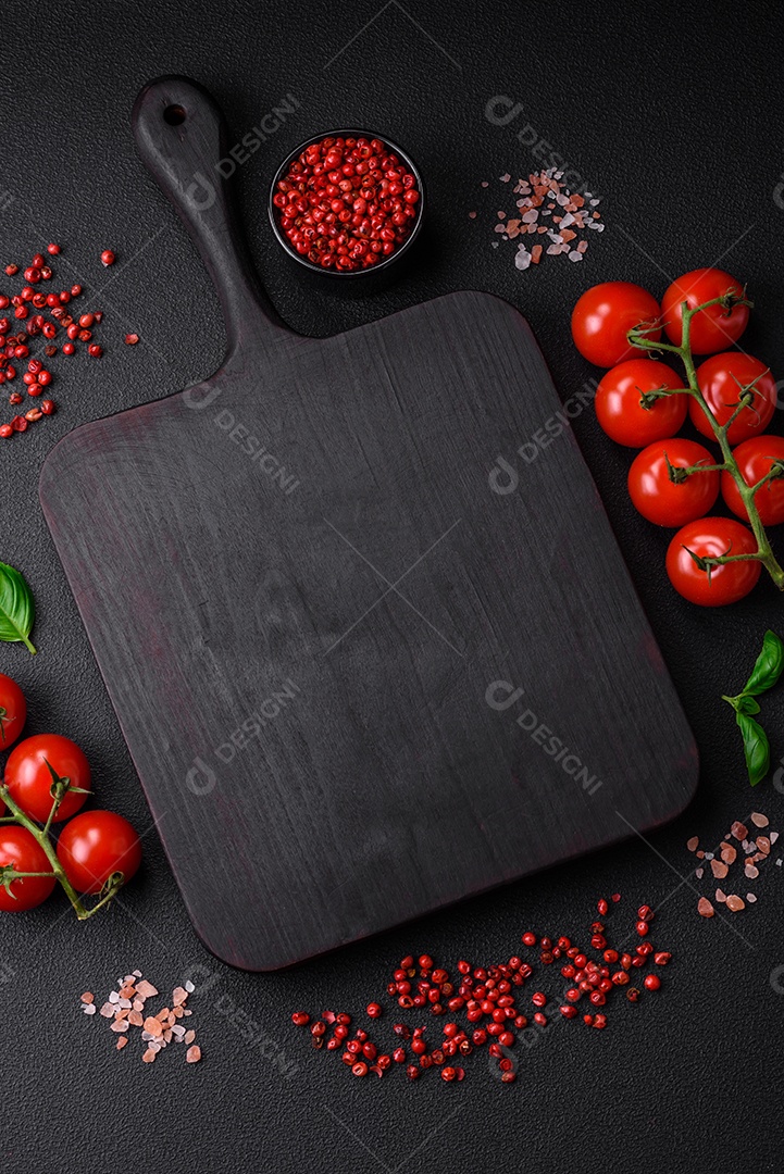 Ingredientes para cozinhar tomate cereja, sal, especiarias e ervas sobre um fundo escuro de concreto