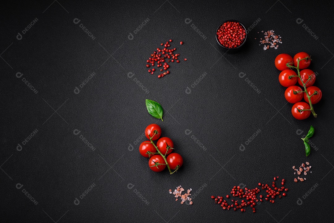 Ingredientes para cozinhar tomate cereja, sal, especiarias e ervas sobre um fundo escuro de concreto