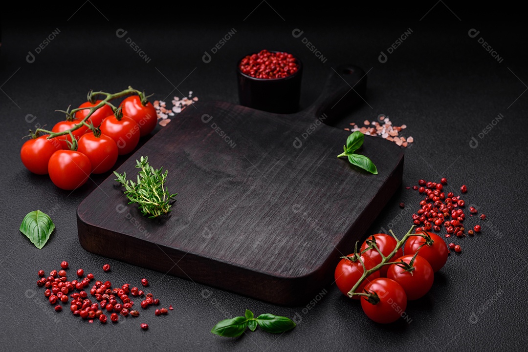 Ingredientes para cozinhar tomate cereja, sal, especiarias e ervas sobre um fundo escuro de concreto