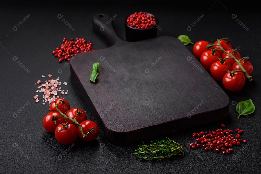 Ingredientes para cozinhar tomate cereja, sal, especiarias e ervas sobre um fundo escuro de concreto