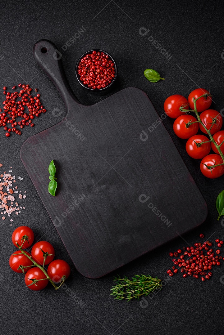 Ingredientes para cozinhar tomate cereja, sal, especiarias e ervas sobre um fundo escuro de concreto