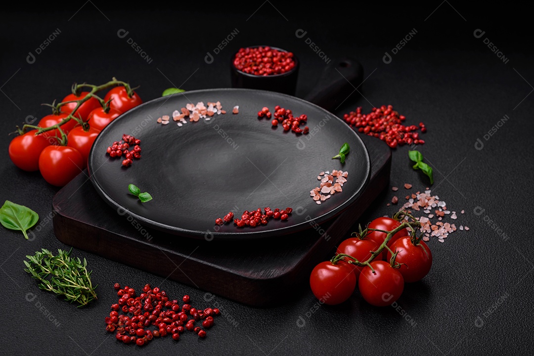 Ingredientes para cozinhar tomate cereja, sal, especiarias e ervas sobre um fundo escuro de concreto