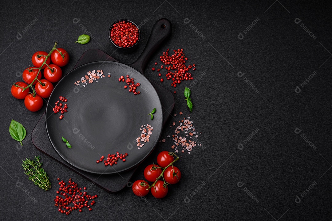 Ingredientes para cozinhar tomate cereja, sal, especiarias e ervas sobre um fundo escuro de concreto