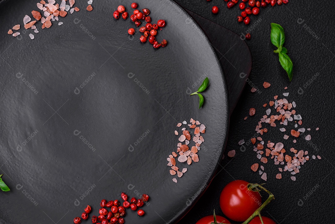 Ingredientes para cozinhar tomate cereja, sal, especiarias e ervas sobre um fundo escuro de concreto