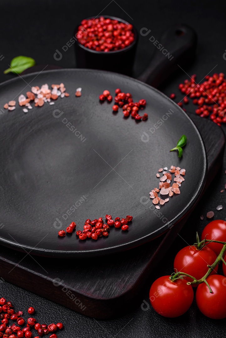 Ingredientes para cozinhar tomate cereja, sal, especiarias e ervas sobre um fundo escuro de concreto