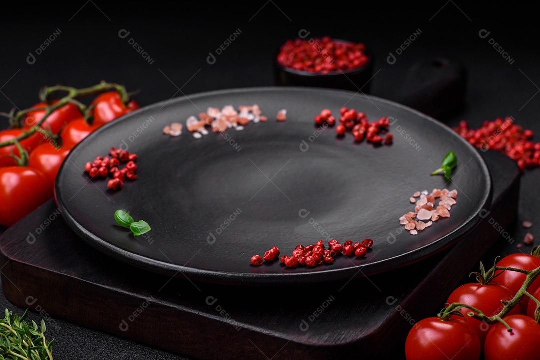 Ingredientes para cozinhar tomate cereja, sal, especiarias e ervas sobre um fundo escuro de concreto