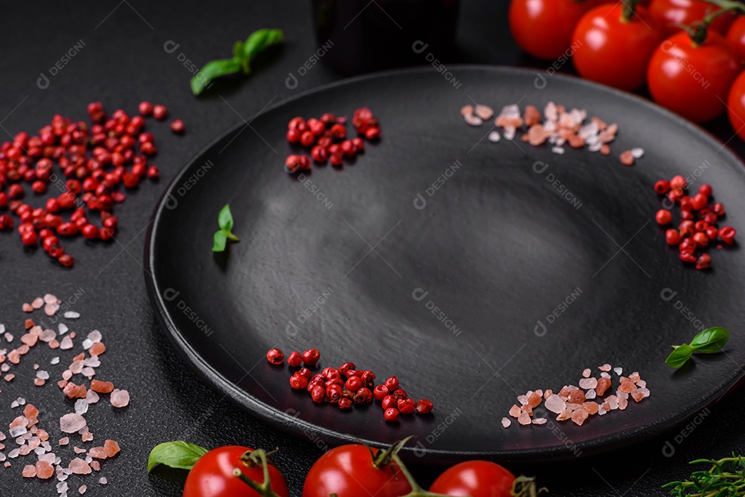 Ingredientes para cozinhar tomate cereja, sal, especiarias e ervas sobre um fundo escuro de concreto